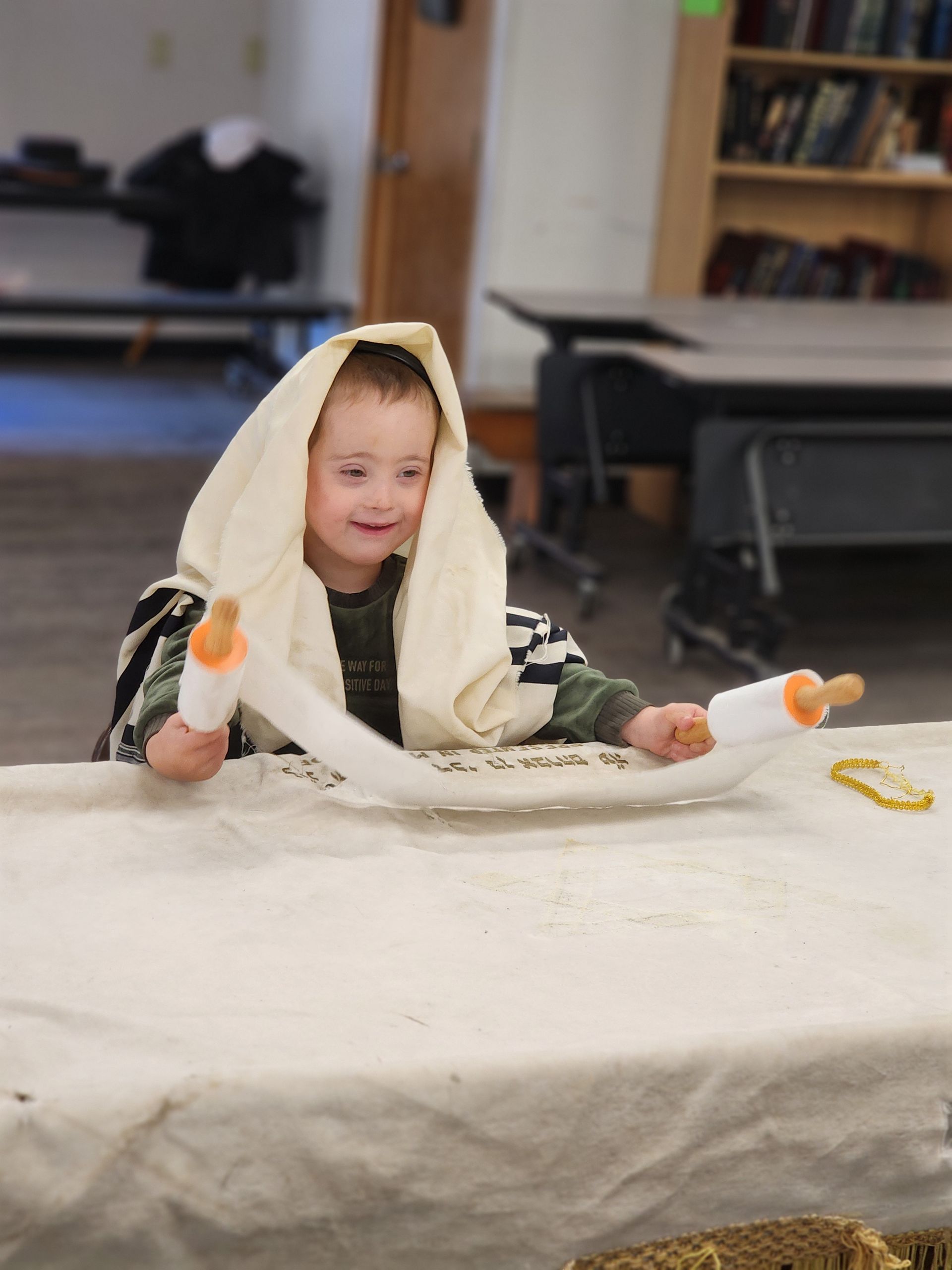 A little boy is sitting at a table holding a scroll