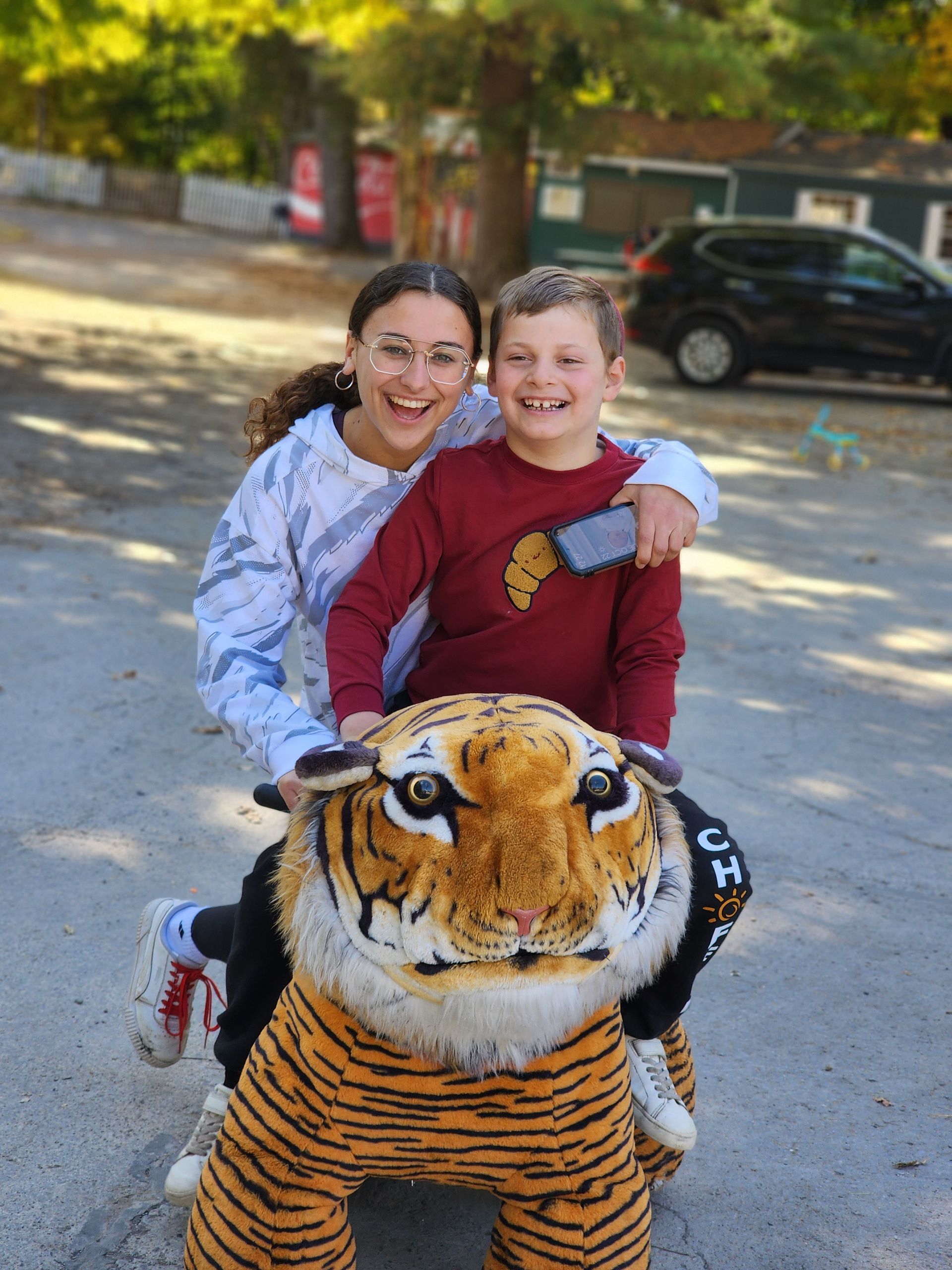 A woman and a boy are riding on the back of a stuffed tiger.