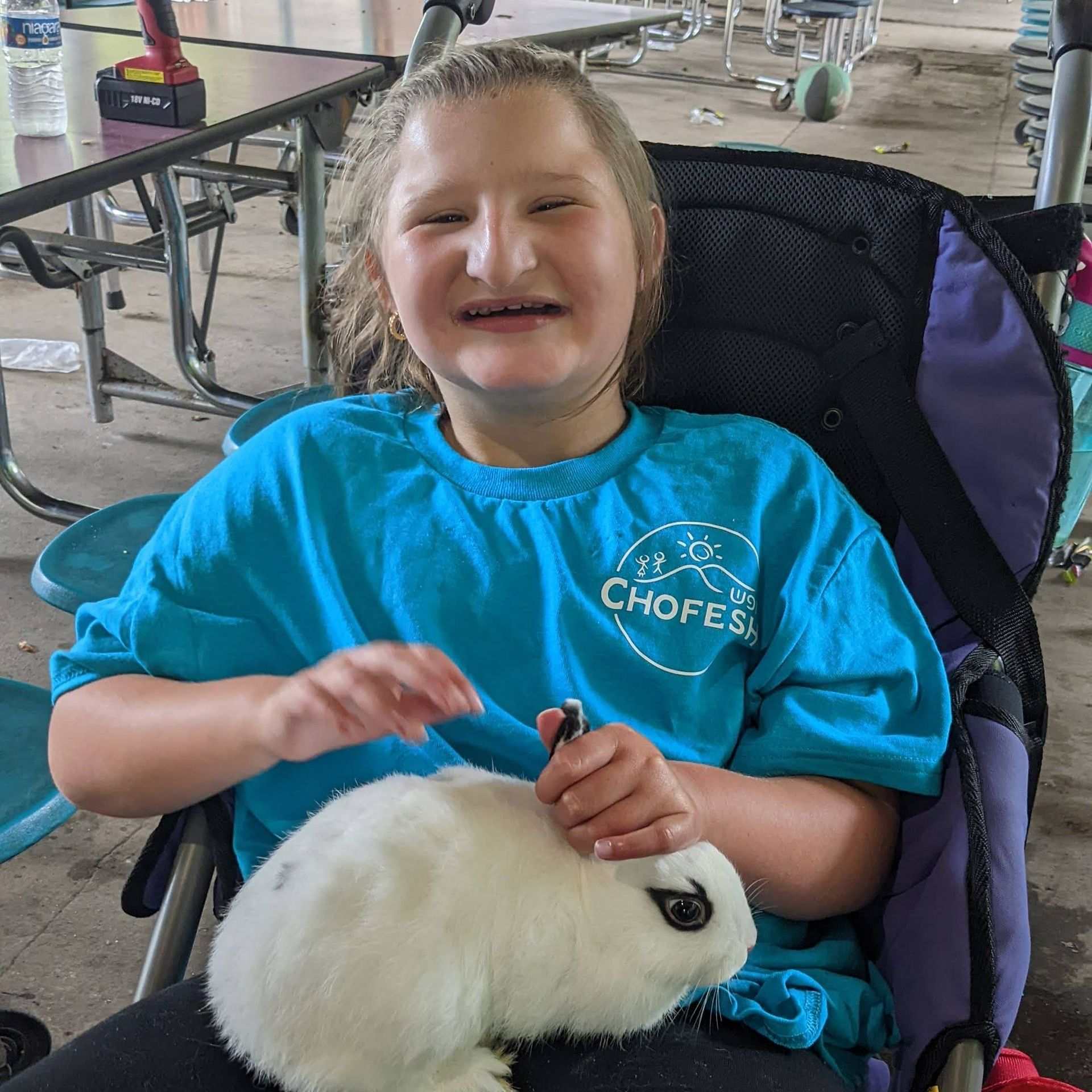 A young girl in a wheelchair is holding a white rabbit.