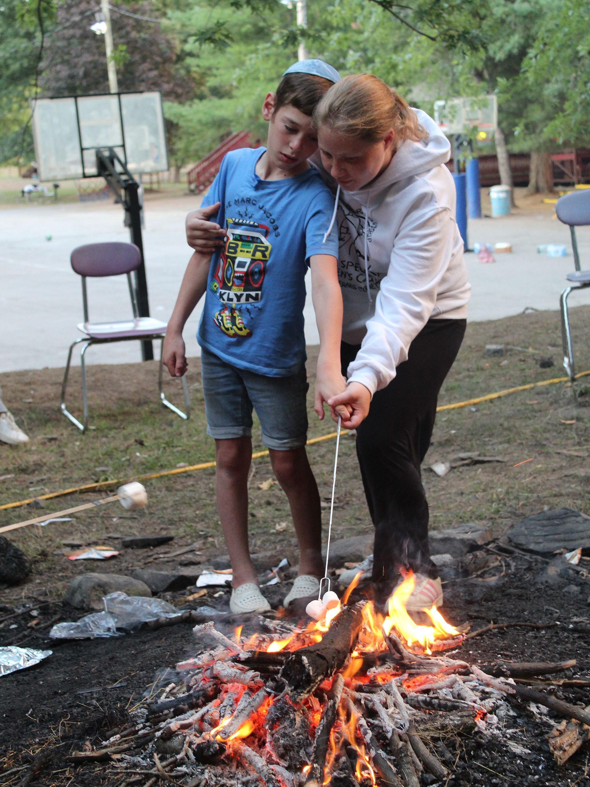 A young boy and a girl are roasting marshmallows over a fire