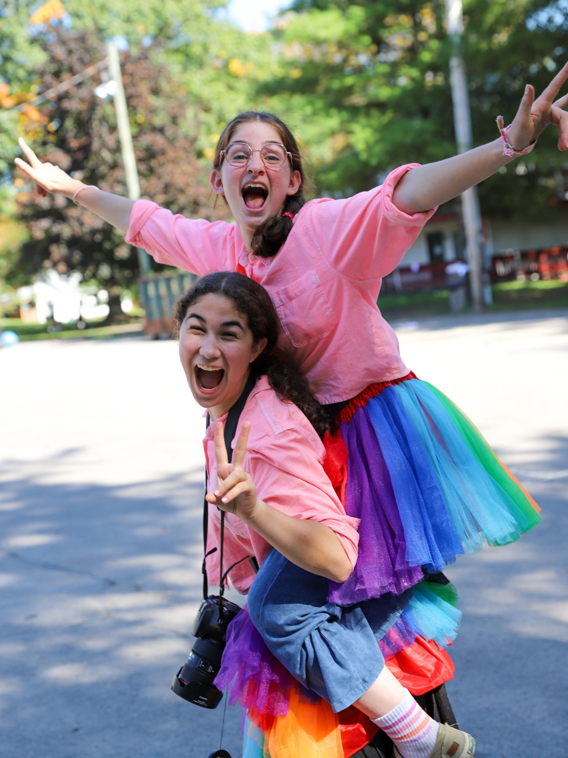 Two girls wearing rainbow skirts are posing for a picture.