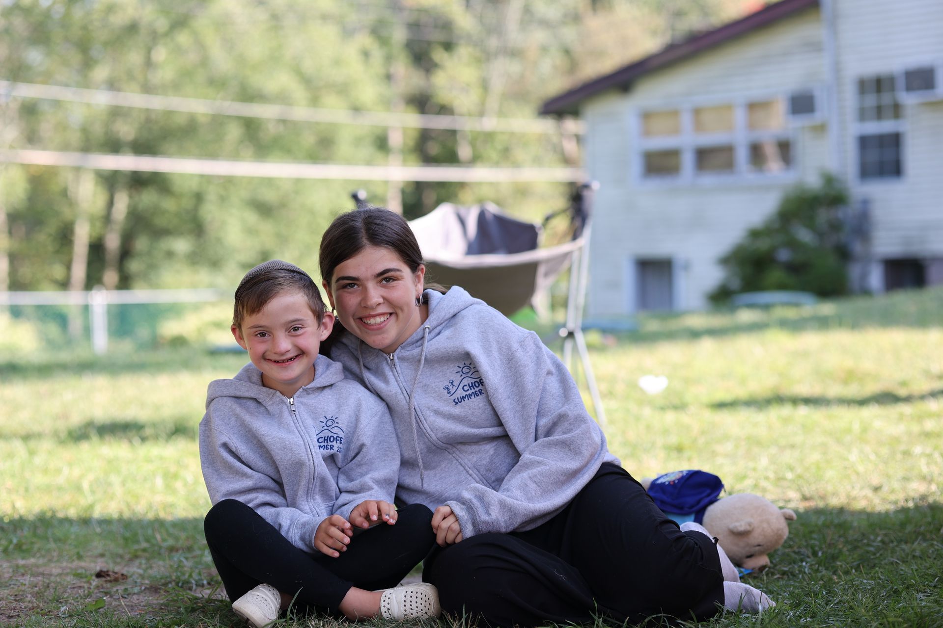 A girl and a young boy are sitting on the grass.