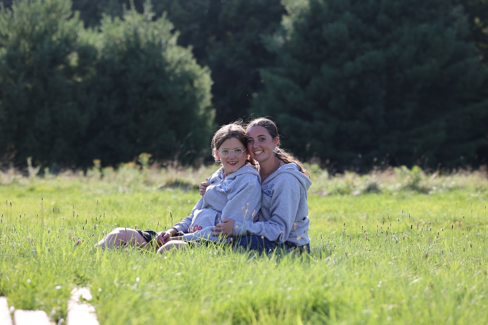 A woman and a child are sitting in a grassy field.