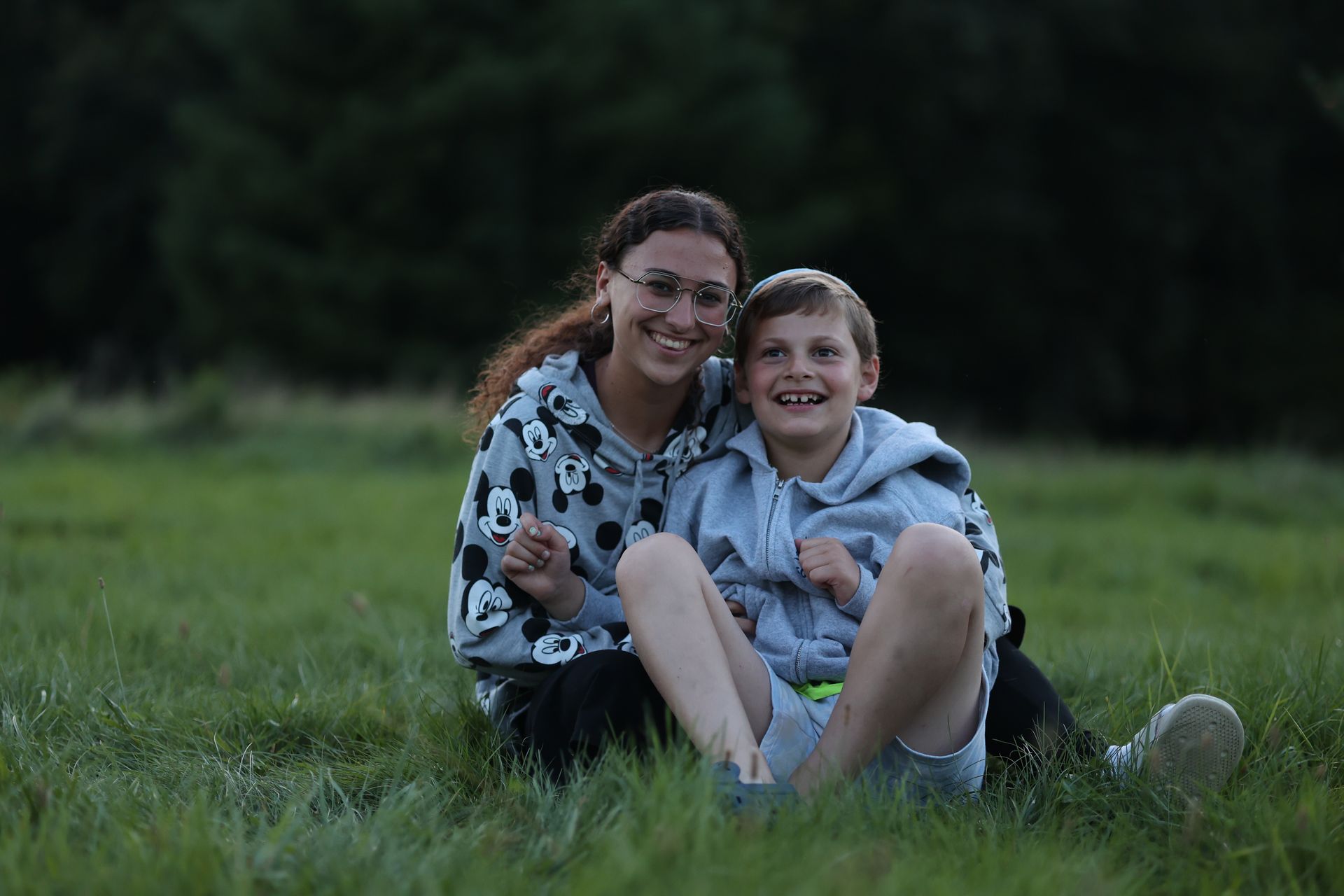 A woman and a boy are sitting in the grass together.