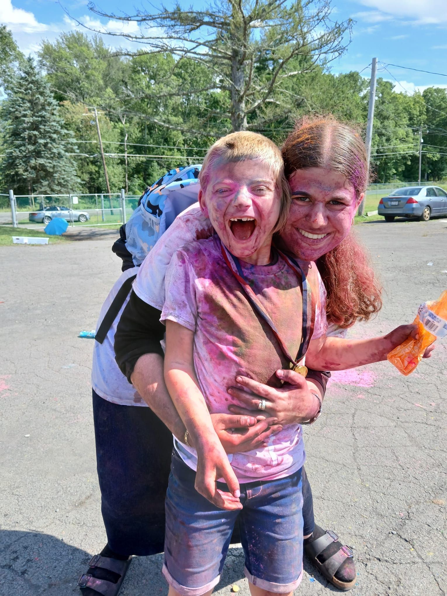 A woman is carrying a boy on her back who is covered in colored powder.