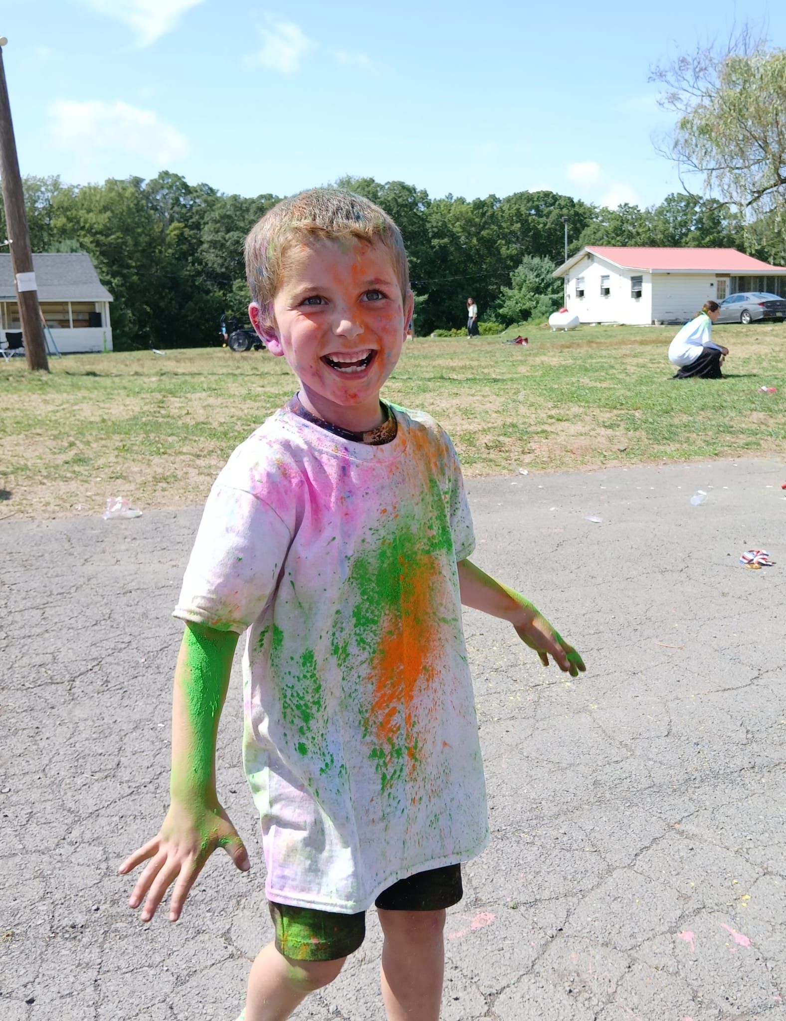 A young boy is covered in colored powder and smiling