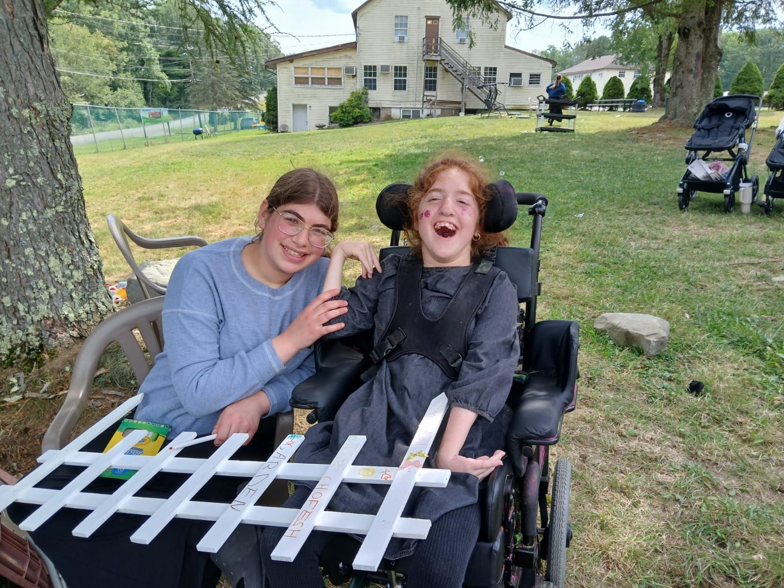 A girl in a wheelchair is sitting next to a boy in a chair.