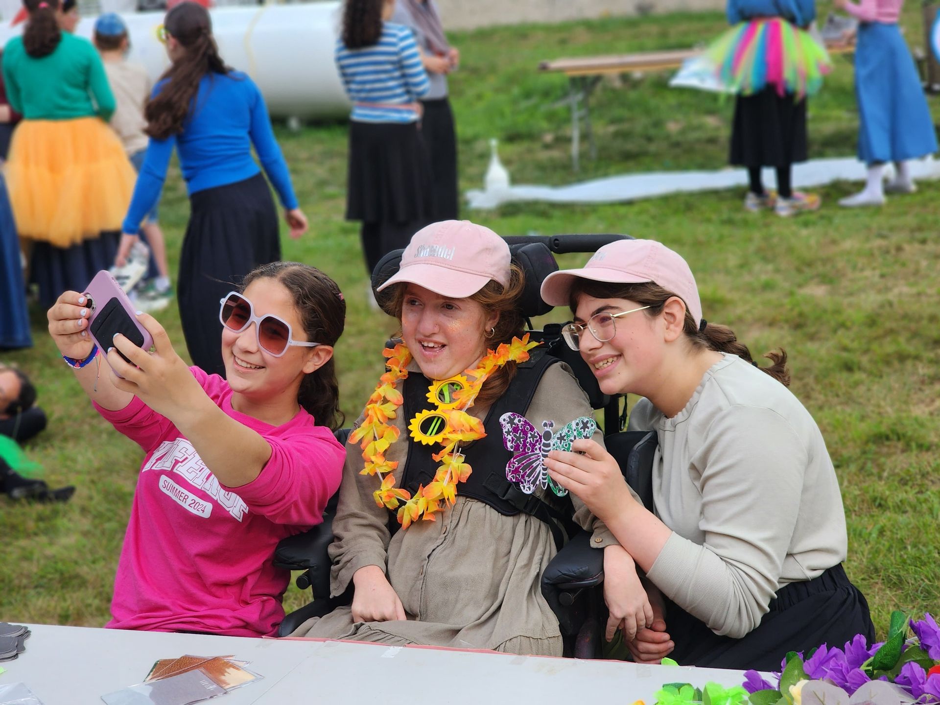 A girl in a wheelchair is taking a selfie with two other girls.