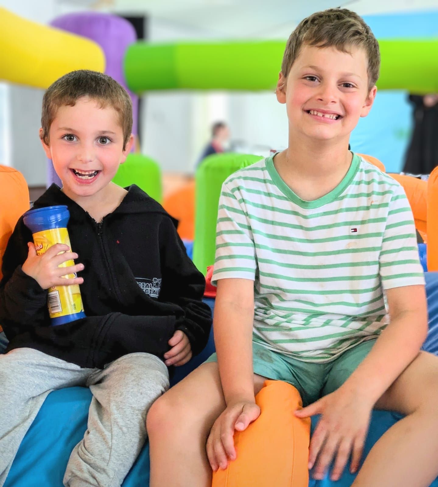 Two young boys are sitting next to each other and smiling