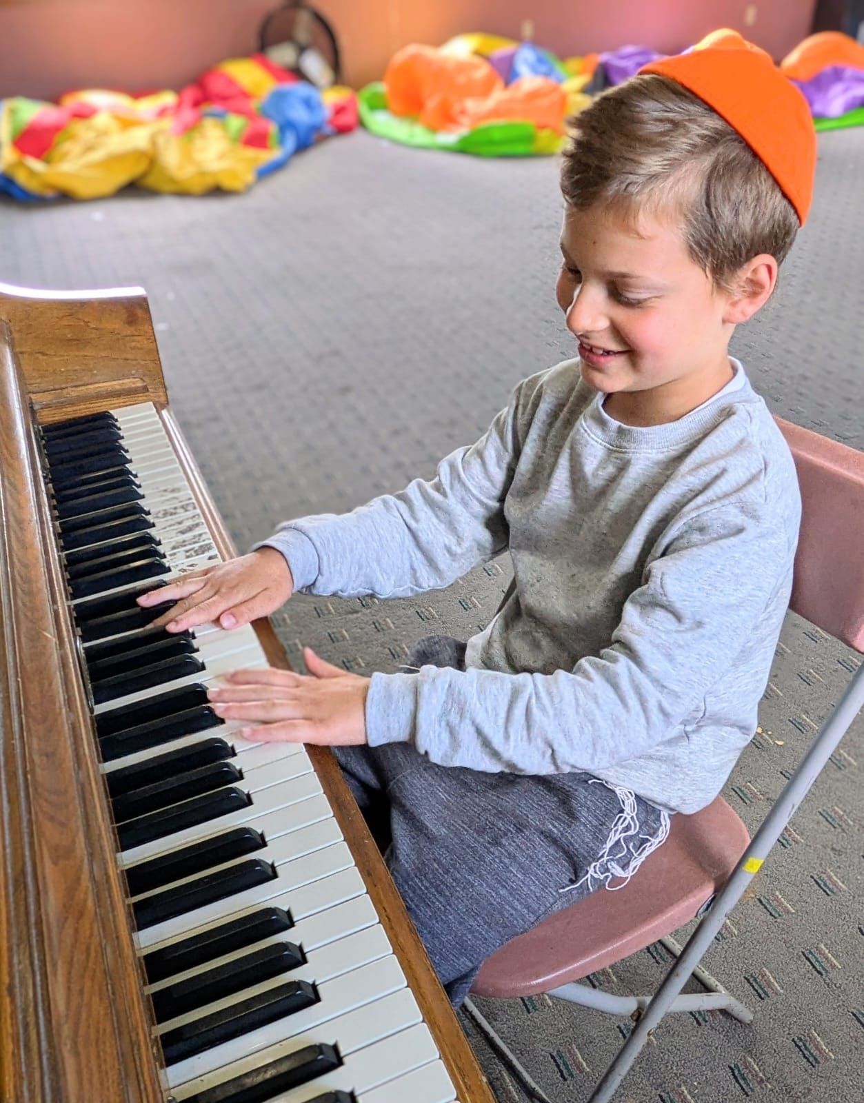 A young boy is sitting in a chair playing a piano.