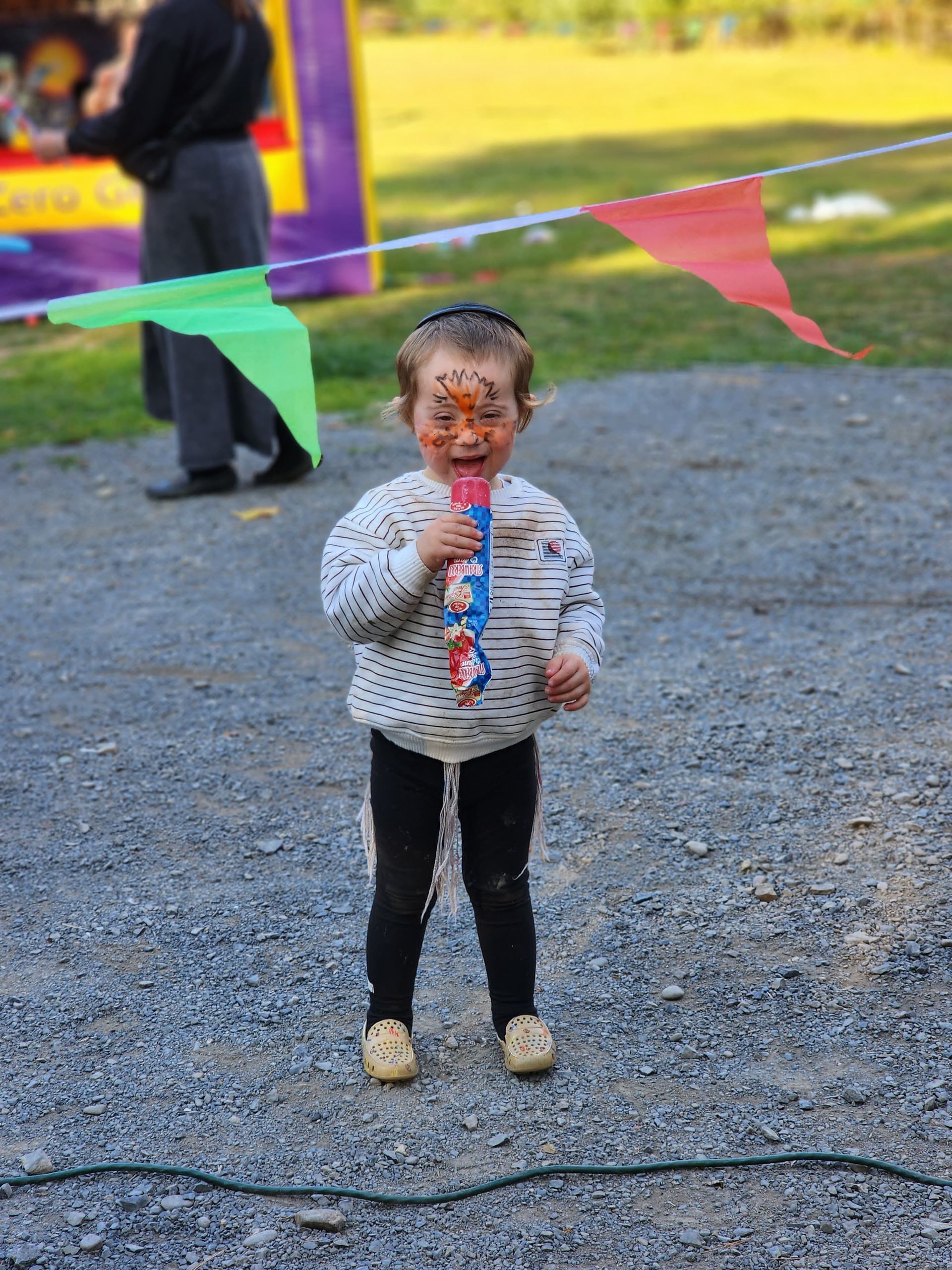 A little girl with her face painted is blowing soap bubbles