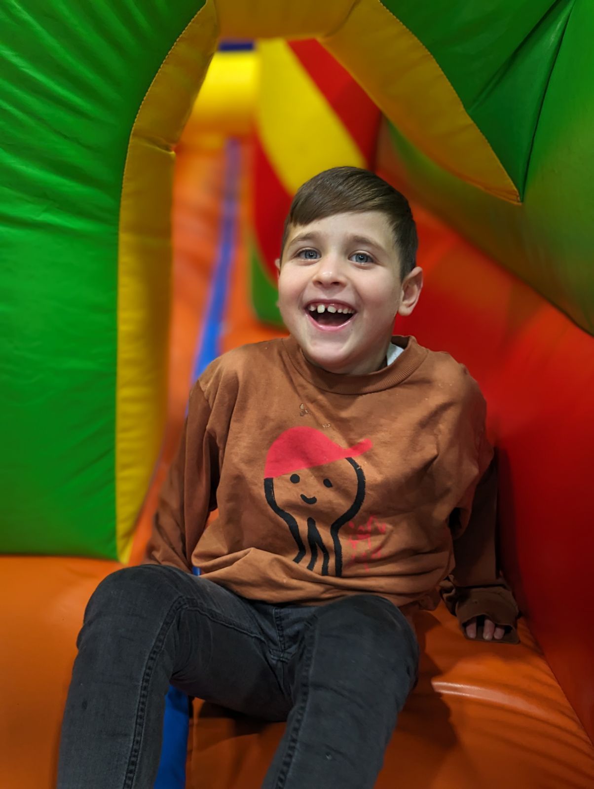 A young boy is in a bouncy house and smiling.