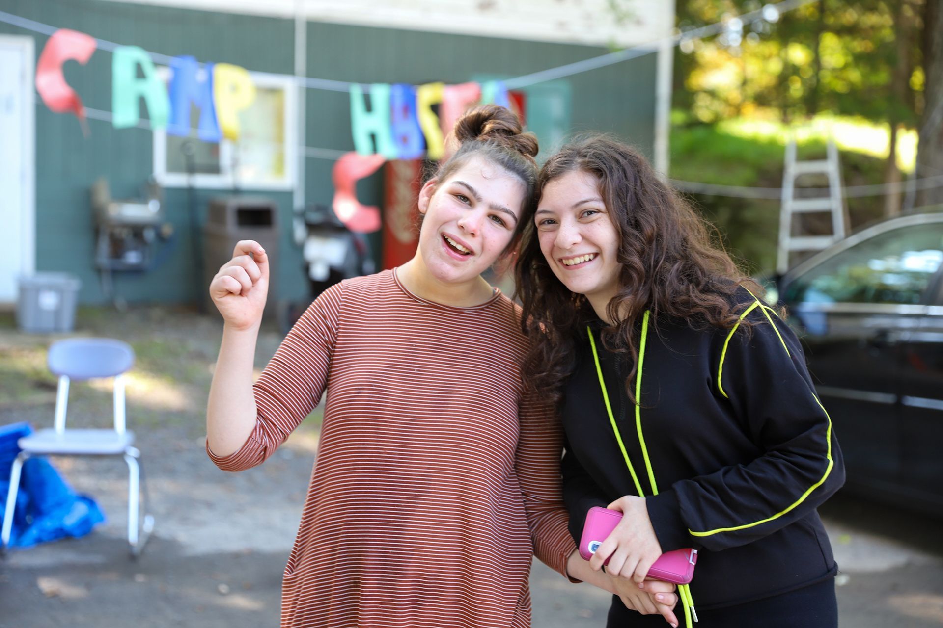 Two girls are posing for a picture in camp.