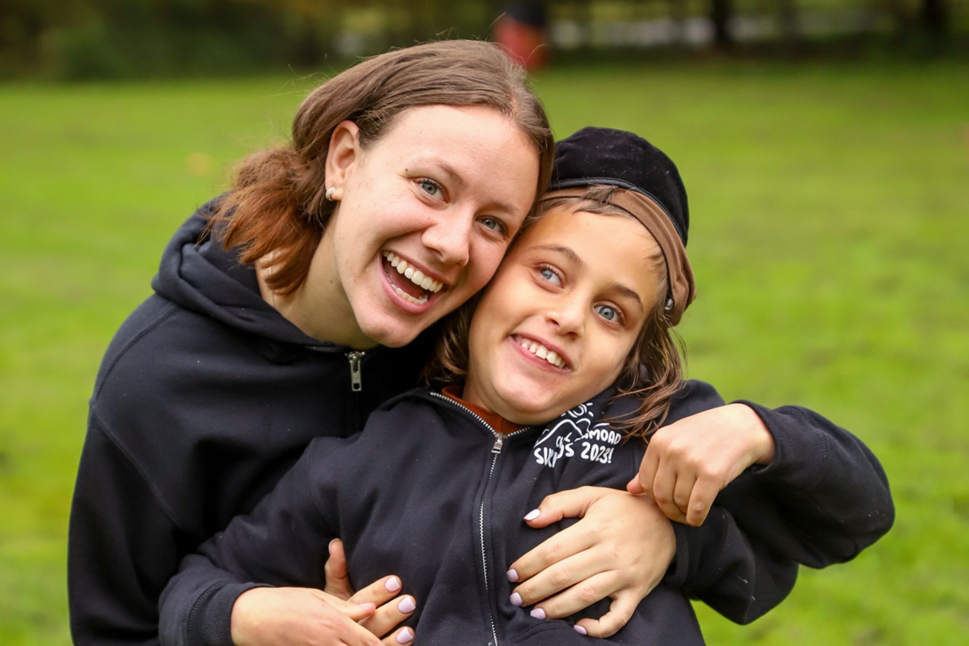 A woman is posing with a young boy in a field.