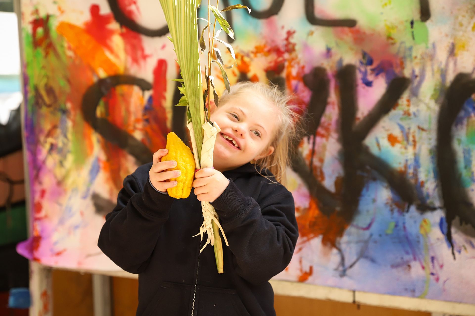 A little girl is holding a lulav and esrog.