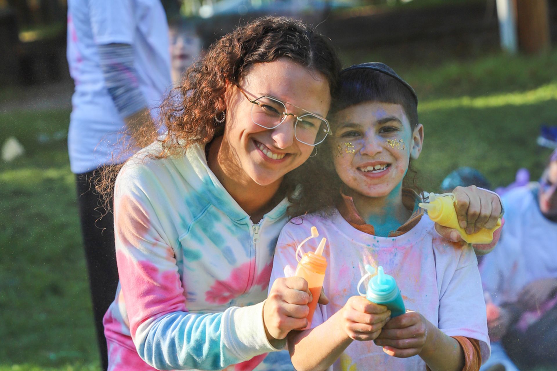 A woman and a young boy are covered in powder paint.