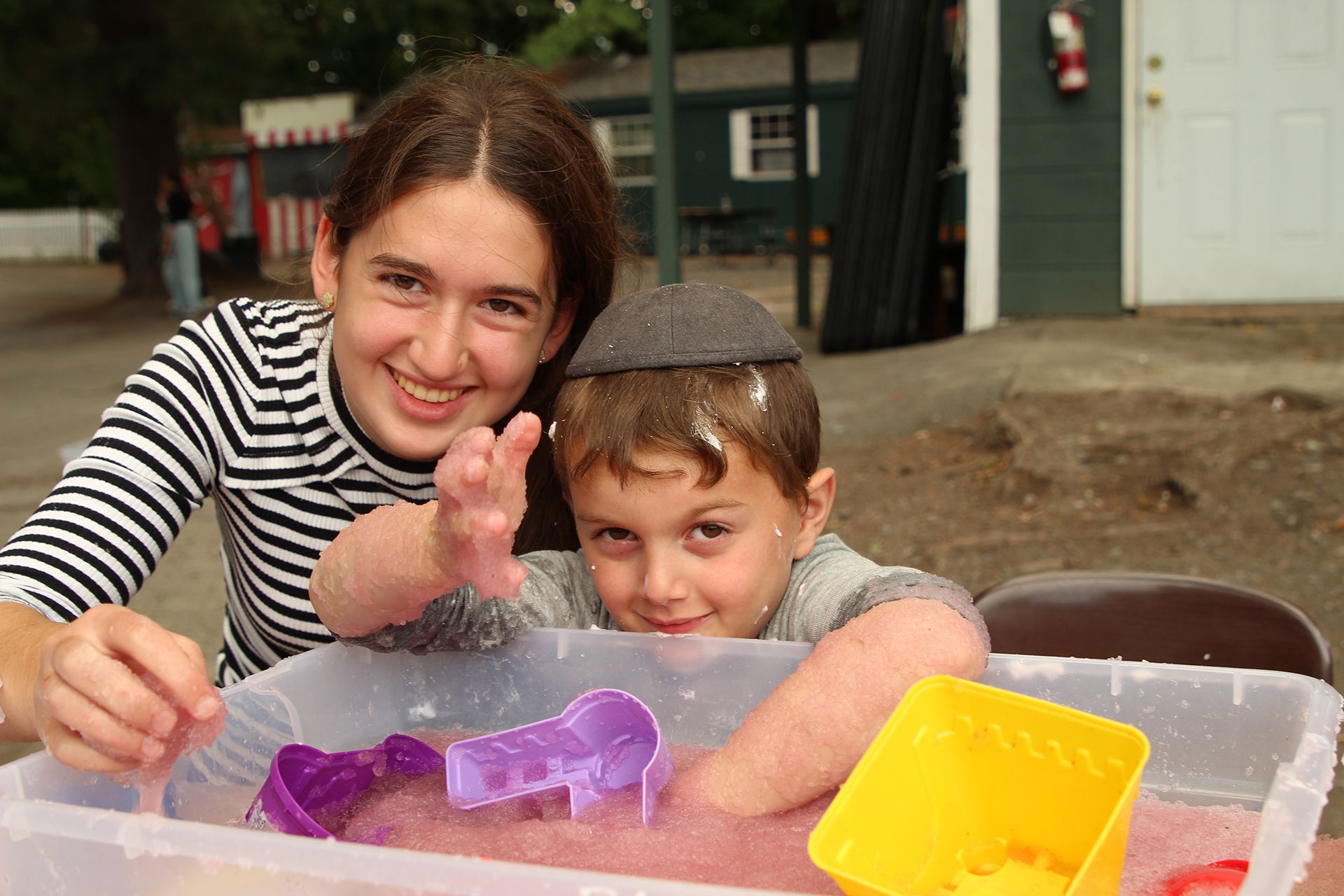 A girl and a boy are playing in a sensory bin.