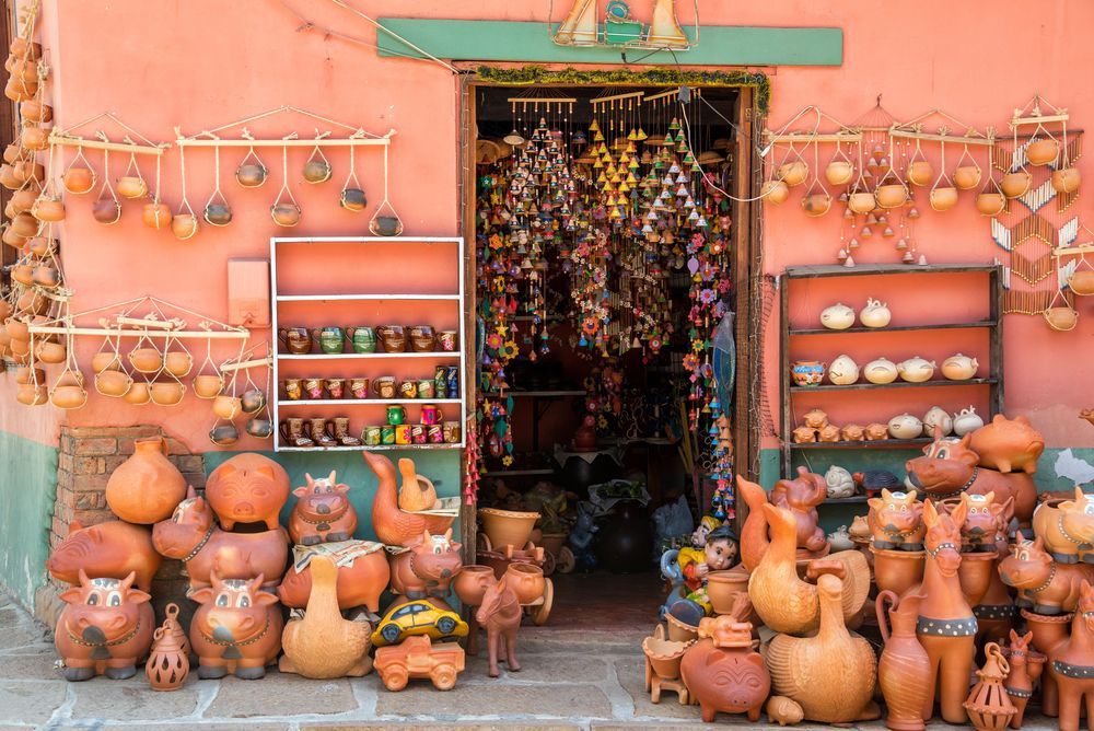 Fachada de tienda con cerámica de terracota, adornos colgantes y artículos expuestos. Paredes color coral