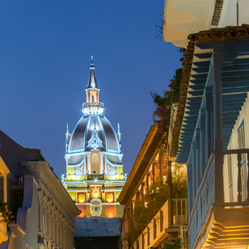 Hombre preparando arreglos florales coloridos, posiblemente para un festival o desfile. Incluye grandes coronas florales.