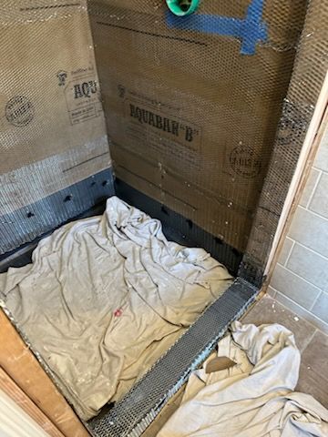 A shower stall is being remodeled with a towel on the floor.