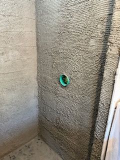 A concrete wall with a green pipe coming out of it.