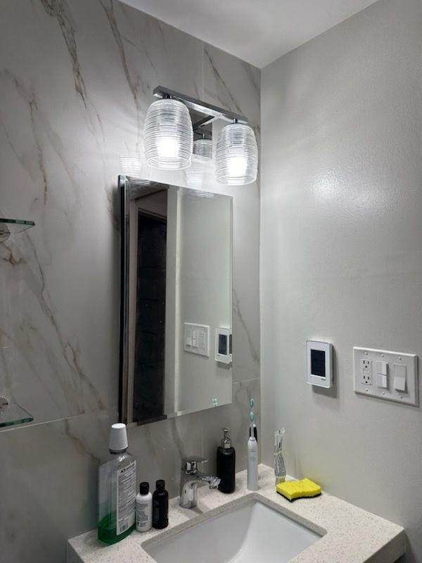 A bathroom with a sink , mirror , and light fixture.