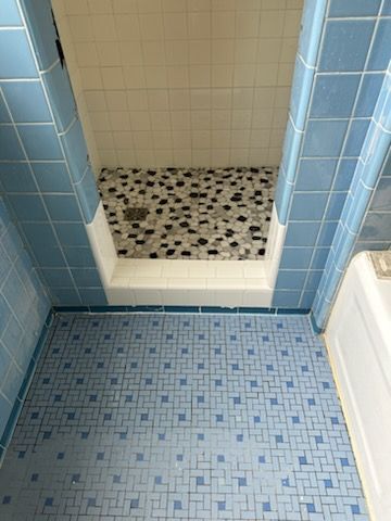 A bathroom with blue tiles and a walk in shower.