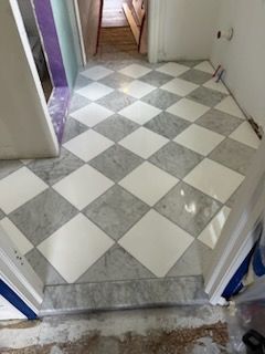 A checkered tile floor in a hallway leading to a bathroom.