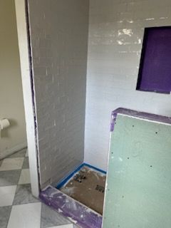 A shower stall is being built in a bathroom with a checkered floor.