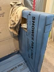 A shower pan liner is sitting on top of a box in a bathroom.