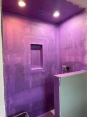 A bathroom with a purple wall and a purple ceiling.