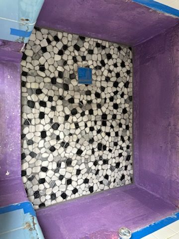 A shower stall with a black and white tile floor and a purple ceiling.