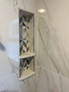 A shower niche in a bathroom with a geometric design on the wall.