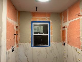 A bathroom under construction with a window in the corner.