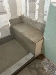 A bathroom under construction with a concrete bench in the corner.