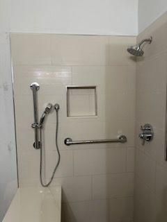 A shower with a hand rail and a shower head.