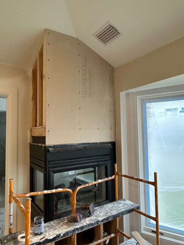 A fireplace is being built in a room with scaffolding around it