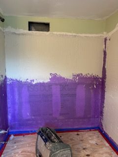 A room with purple and white walls and a bag on the floor.
