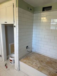 A bathroom with white tiles and a wooden floor.