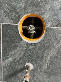 A close up of a hole in a wall with a pipe coming out of it.