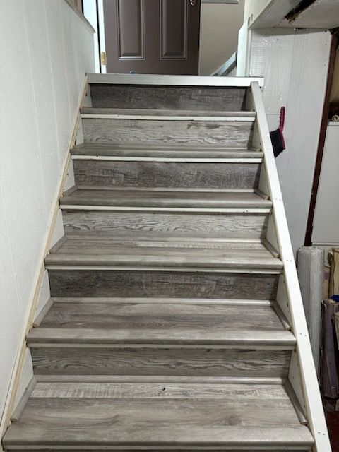 A set of wooden stairs leading up to a door in a house.
