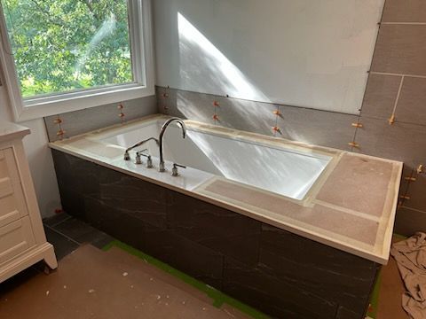 A bathtub is being built in a bathroom next to a window.