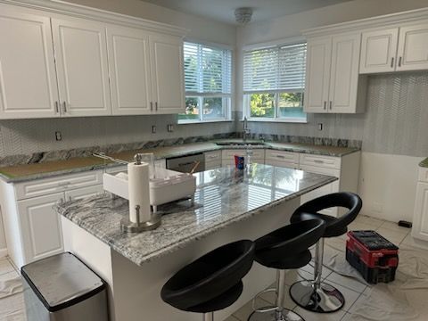 A kitchen with white cabinets and granite counter tops is being remodeled.