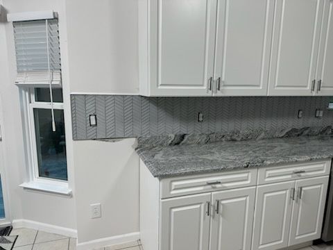 A kitchen with white cabinets and granite counter tops.