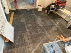 A room with a black floor and a ladder in it.