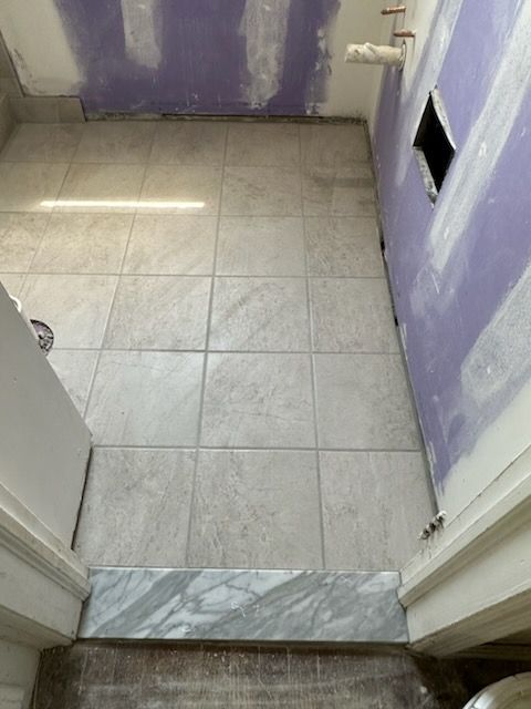 A bathroom under construction with tile floors and purple walls.