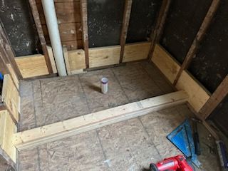 A bathroom under construction with a toilet and a drill on the floor.
