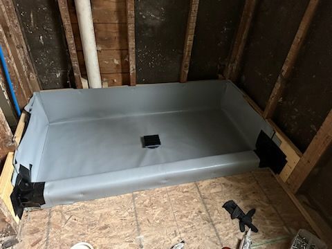 A shower stall is being built in a bathroom under construction.