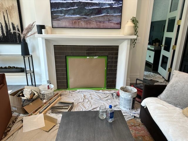A living room with a fireplace that is being painted.