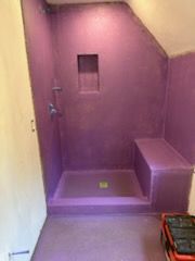 A bathroom with purple walls and a purple shower stall.
